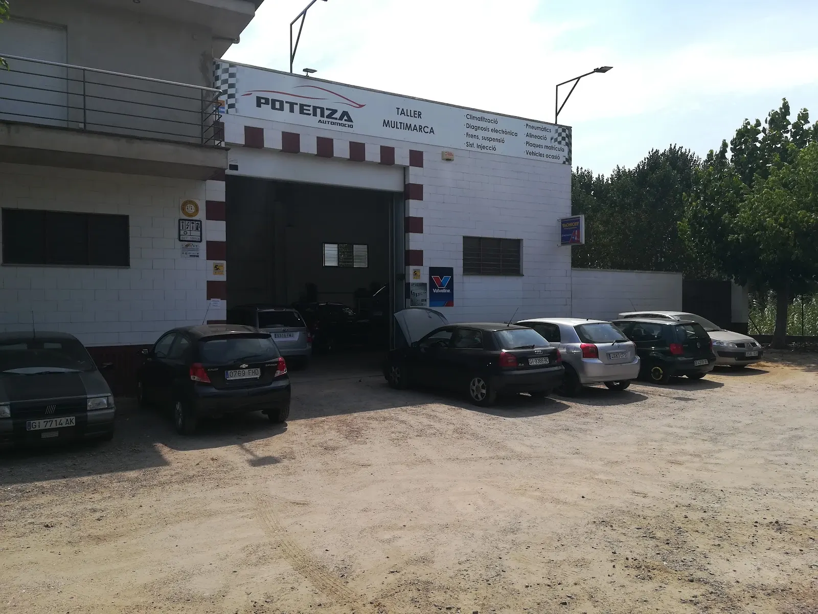Fachada del taller en la C-63 con coches de clientes